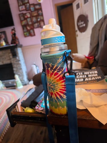 Reviewer's Cirkul Frosted Refreshers water bottle in a colorful tie-dye sleeve with a blue carrying strap.