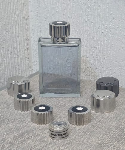 Customer's Montblanc StarWalker perfume bottle surrounded by several metal perfume caps on a flat surface.