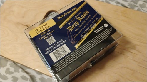 Customer's 24K Hybrid Infused Top Shelf Pre Rolls box resting on a wooden surface.