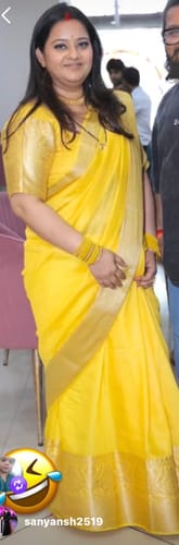 Customer's Elite Ensemble Crepe Georgette Silk Saree in bright yellow with gold border worn by a person.