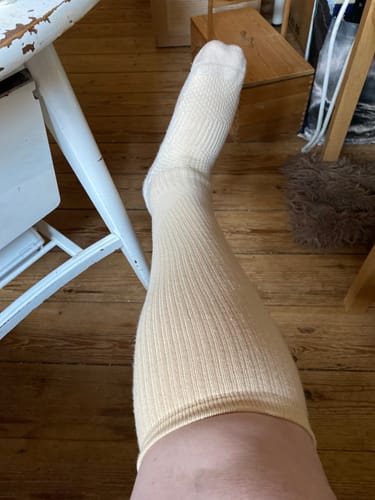 Kundens Støttestrømper i lys beige, båret på benet i et indendørs miljø.