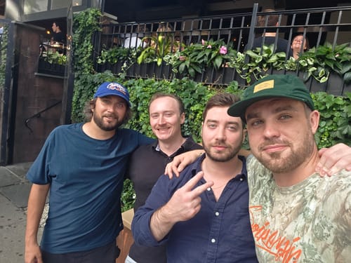 Customer's green Big Camp Hat worn by a person posing outdoors with three other people.