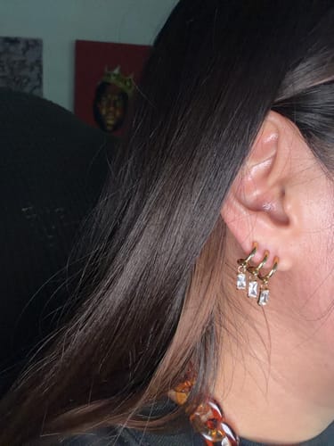Customer's Mirelia earrings, showing three small, gold-toned hoop earrings with crystal-like rectangular charms.
