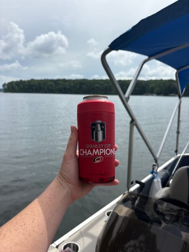Customer's red Carolina Hurricanes Stanley Cup Champions Universal Buddy can cooler held on a boat on a lake.