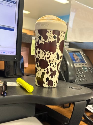 Customer's Cowabunga To-Go Buddy cup with a brown and cream cow print sitting on an office desk.