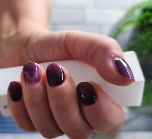 Reviewer's Twilight Ombré UV Gel nail wraps in a black and purple gradient on manicured fingernails.