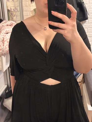 Reviewer's black Matan jumpsuit showing the front twisted design while holding a phone in a mirror selfie