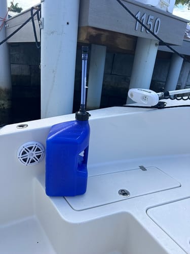 Customer's blue Tuff Jug utility container with an upright spout, resting on the deck of a boat at a dock.