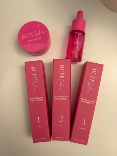 Reviewer's Buff Lashes Korean Lash Lift System pink bottles and boxes arranged on a white surface.