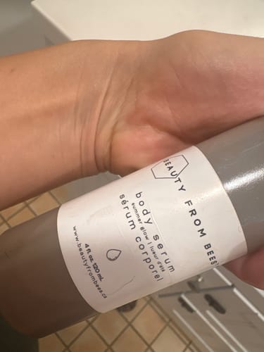 Customer's hand holding a bottle of Beauty From Bees Body Serum - Summer Glow