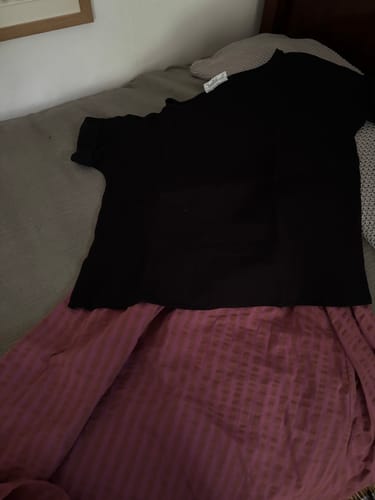 Avis client : Blouse Romy noire posée sur une jupe rose, montrant le contraste des couleurs et la texture du tissu.