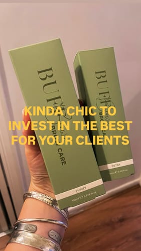 Customer's hand holding two olive green Brow Care Purify bottles against a plain background.