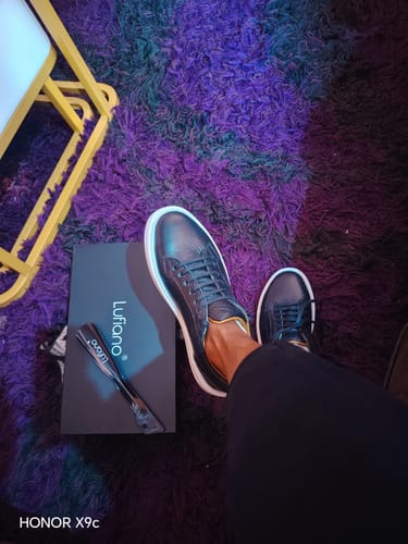 Reviewer's black Lufiano lace-up shoe worn on foot, next to a product box on a purple textured rug.