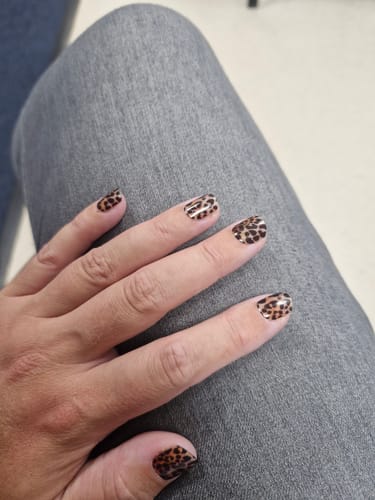Customer's hand showing long, manicured nails with leopard print designs from the Holy Gels Starter Kit.