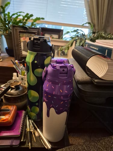 Customer's purple Bottle Buddy with ice cream print sitting on a desk next to another bottle and office supplies.