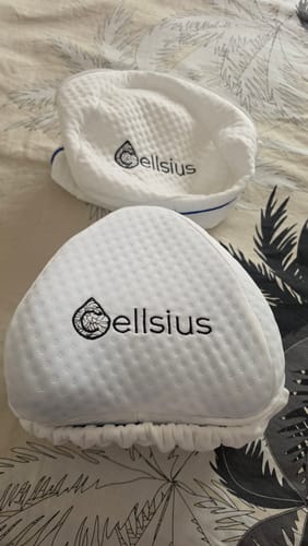 Customer's two white, textured Cellsius knee pillows resting on a patterned bed sheet.