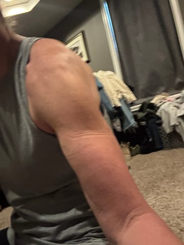Customer's arm wearing a grey tank top while using the B STRONG bands during a training session.