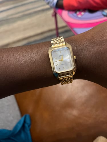 Customer's gold Claire De Mains watch with a metal link band worn on the wrist.