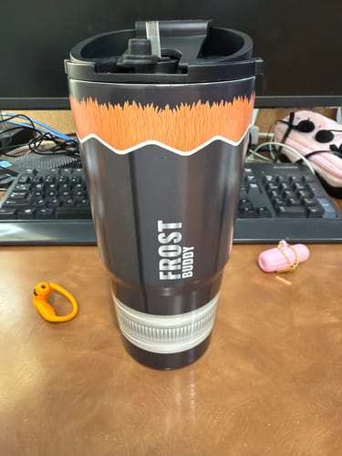 Customer's dark gray Mystery To-Go Buddy tumbler with an orange patterned top, sitting on a desk.