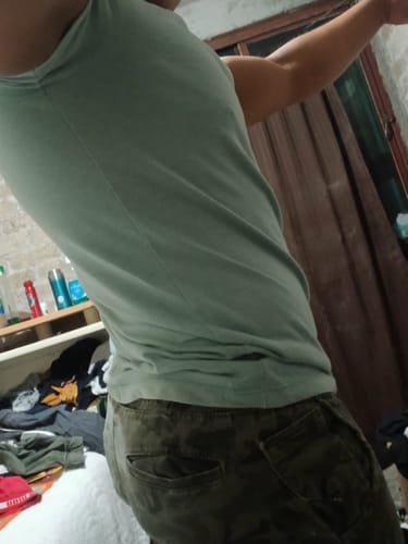 Customer's side view of a person wearing a light green tank top, reflecting on the Trenbol 100 usage.