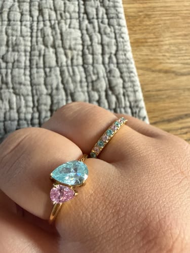 Customer's Leesha Birthstone Ring with blue and pink pear-cut stones, worn on a hand next to a colorful eternity ring.