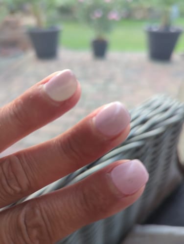 Reviewer's hand showing Blush Radiance UV gel nail wraps in a soft pink shade after two weeks of wear.