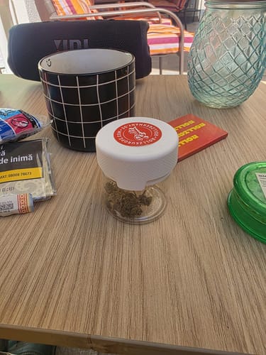 Customer's Gary Payton flower in a small, clear, reusable airtight jar placed on a wooden table.