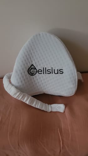 Customer's white Cellsius orthopedic knee pillow with a strap, placed on a surface.