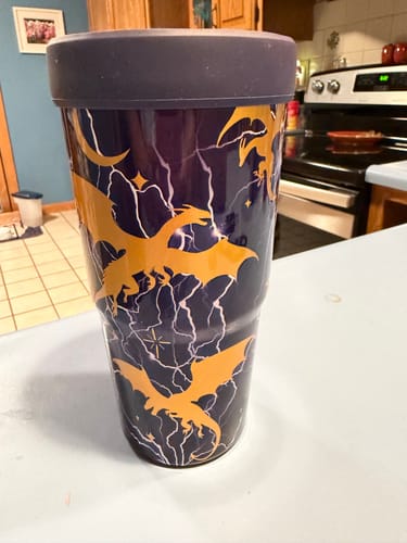 Customer's To-Go Buddy tumbler on a kitchen counter, featuring a dark purple design with orange dragon and bolt graphics.