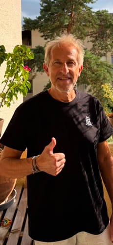 Customer's black Collection Mc Queen t-shirt with logo, worn by a smiling person giving a thumbs up.