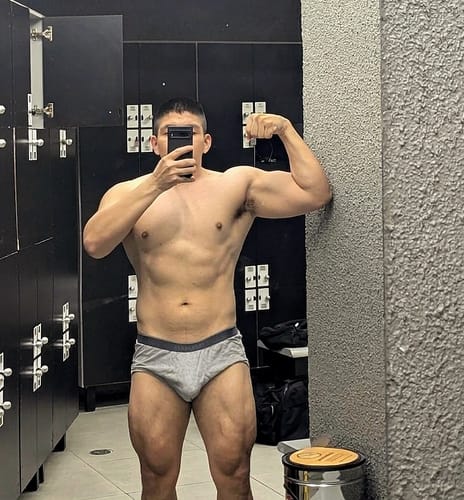 Customer's muscular physique in a locker room, demonstrating results from the Ciclo Fuerza Total, posing to show progress.