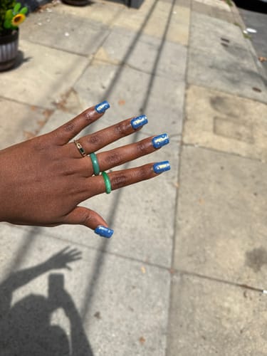 Customer's hand wearing the MAKEDA Jade Ring and another ring on a sidewalk
