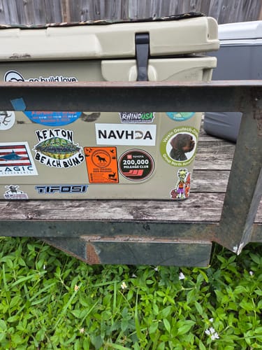 Customer's custom vinyl stickers applied to the side of a tan cooler, showing vibrant designs and quality.