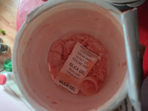 Customer's open container of OSMO electrolyte hydration blend, showing the pink powder, a scoop, and a silica gel packet.