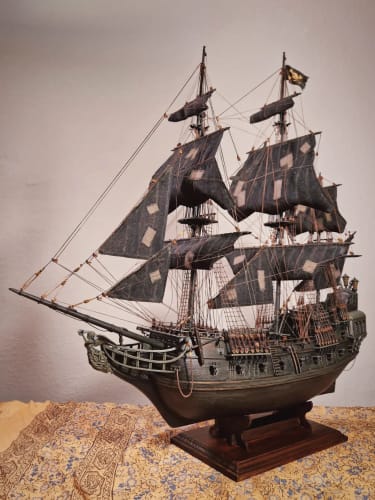 Customer's completed Cisne Negro maqueta ship model with black sails on a wooden stand.