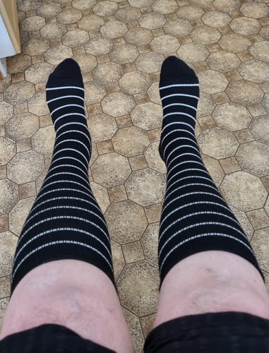 Kunds ben iklädda svarta, randiga Diasocks stödstrumpor.