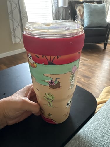Customer's To-Go Buddy cup with a festive beach and spooky themed design held in a hand