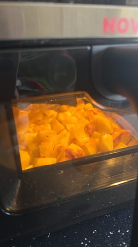 Reviewer's Air Fryer Novio StonePro showing golden, cooked potatoes through the clear viewing window.