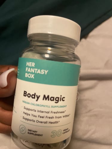 Customer's hand holding a bottle of Body Magic Chlorophyll Pill with a teal and white label.