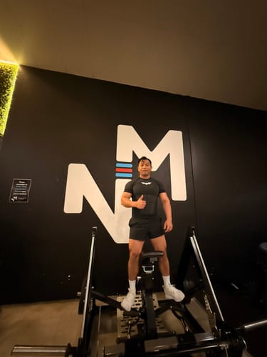 Reviewer's Batman Compression Tee, black and fitted, worn in a gym setting while giving a thumbs up.