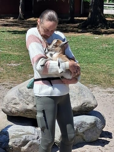 Reviewer's FeelFree Dog Walker Tights in green, worn while holding a goat outdoors.