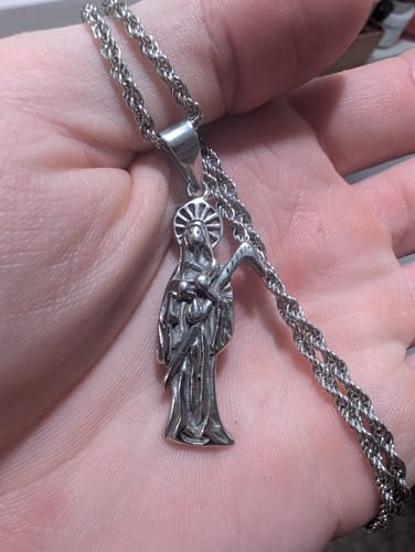 Reviewer's silver rope chain and Santa Muerte pendant held in hand.