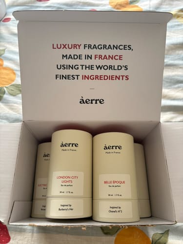 Customer's opened box containing five beige cylindrical Wildfire perfume bottles.