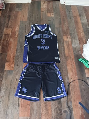Customer's purple and white basketball jersey and matching shorts set laid flat on a wooden floor.