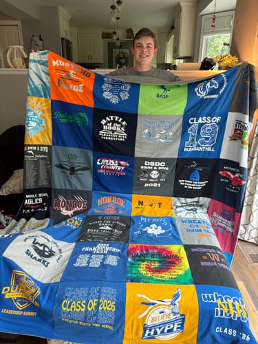 Customer's Project Repat T-Shirt Quilt held by a person, showing colorful school and sports t-shirt squares.