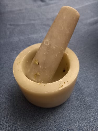 Customer's Mortero Mármol mortar and pestle, showing the small, textured stone tool being used for spices.
