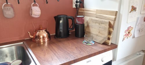 Kundens Walnut Deep kontaktplast montert på en kjøkkenbenk med mørkt treutseende ved siden av en vannkoker.