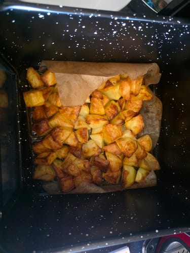Customer's Air Fryer Novio StonePro basket filled with golden-brown roasted potato cubes on parchment paper.