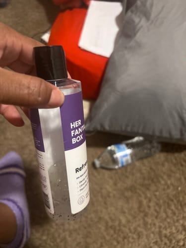 Customer's hand holding a bottle of Yummy Organic Body Wash with a white and purple label