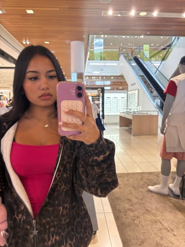 Reviewer wearing a brown leopard print W533 Flashback Zip Hoodie over a pink top while taking a mirror selfie.